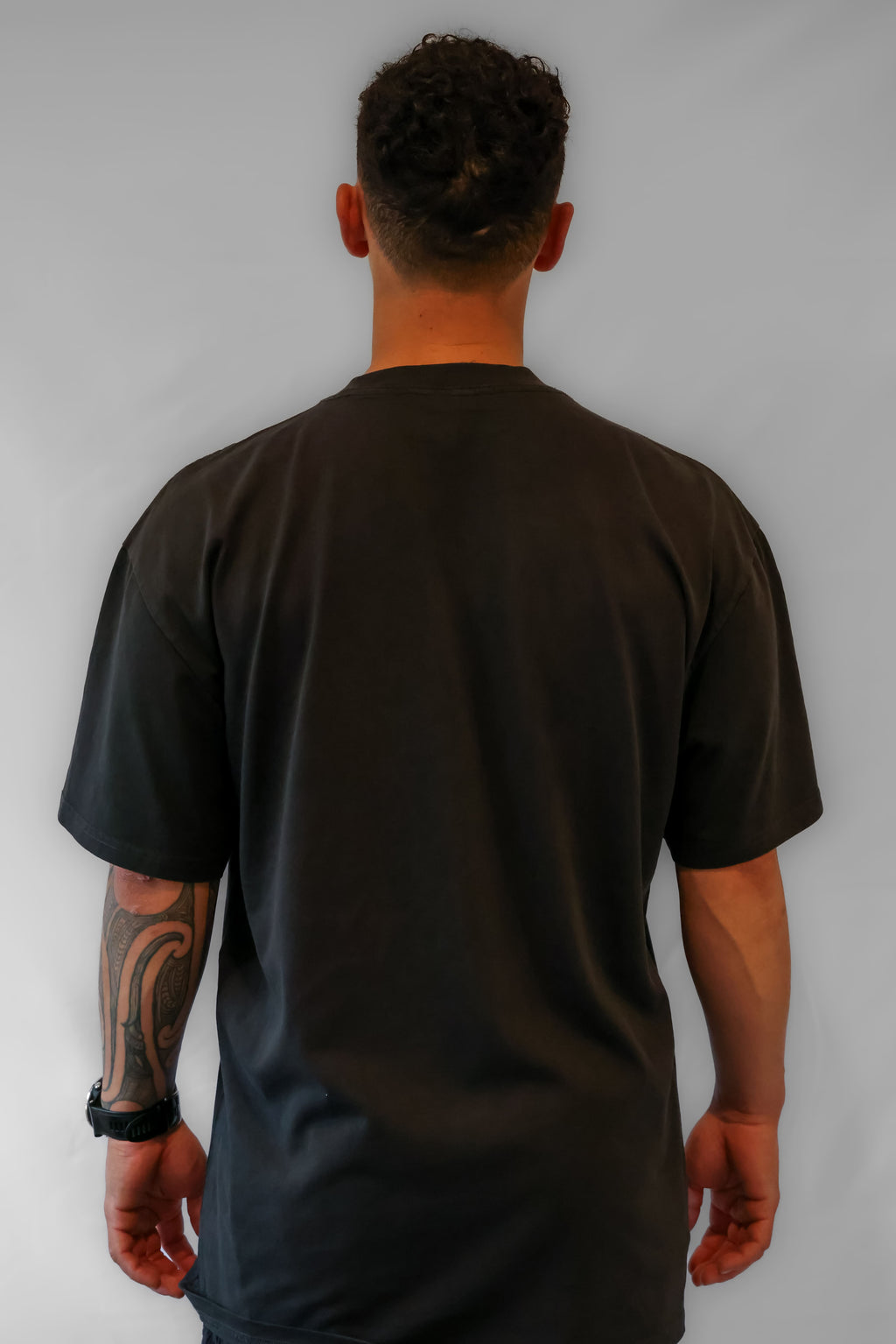 Person wearing a faded black t-shirt against a grey background