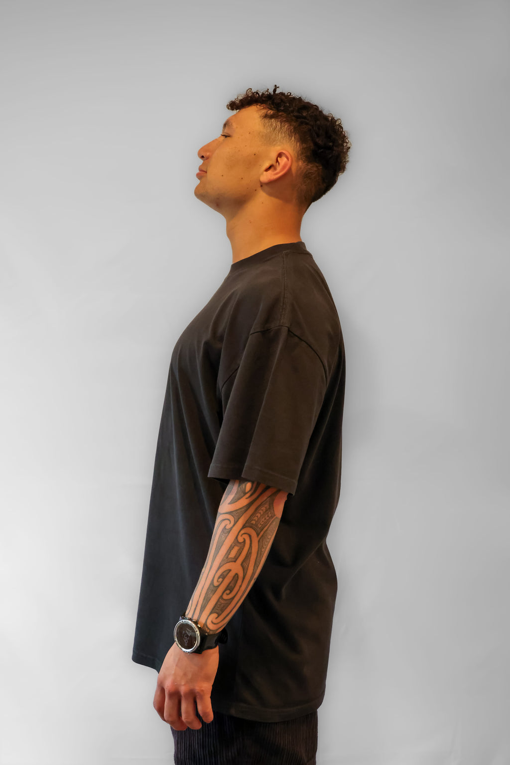 Person wearing a faded black t-shirt against a grey background