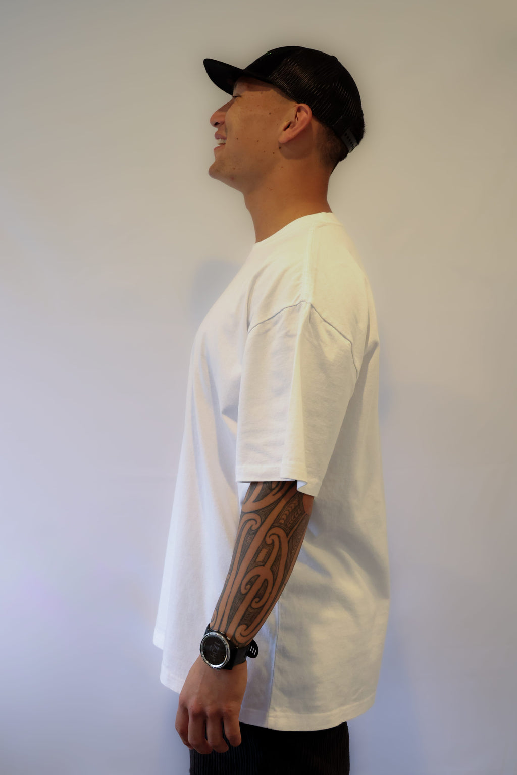 Man wearing a white t-shirt and black cap against a plain background