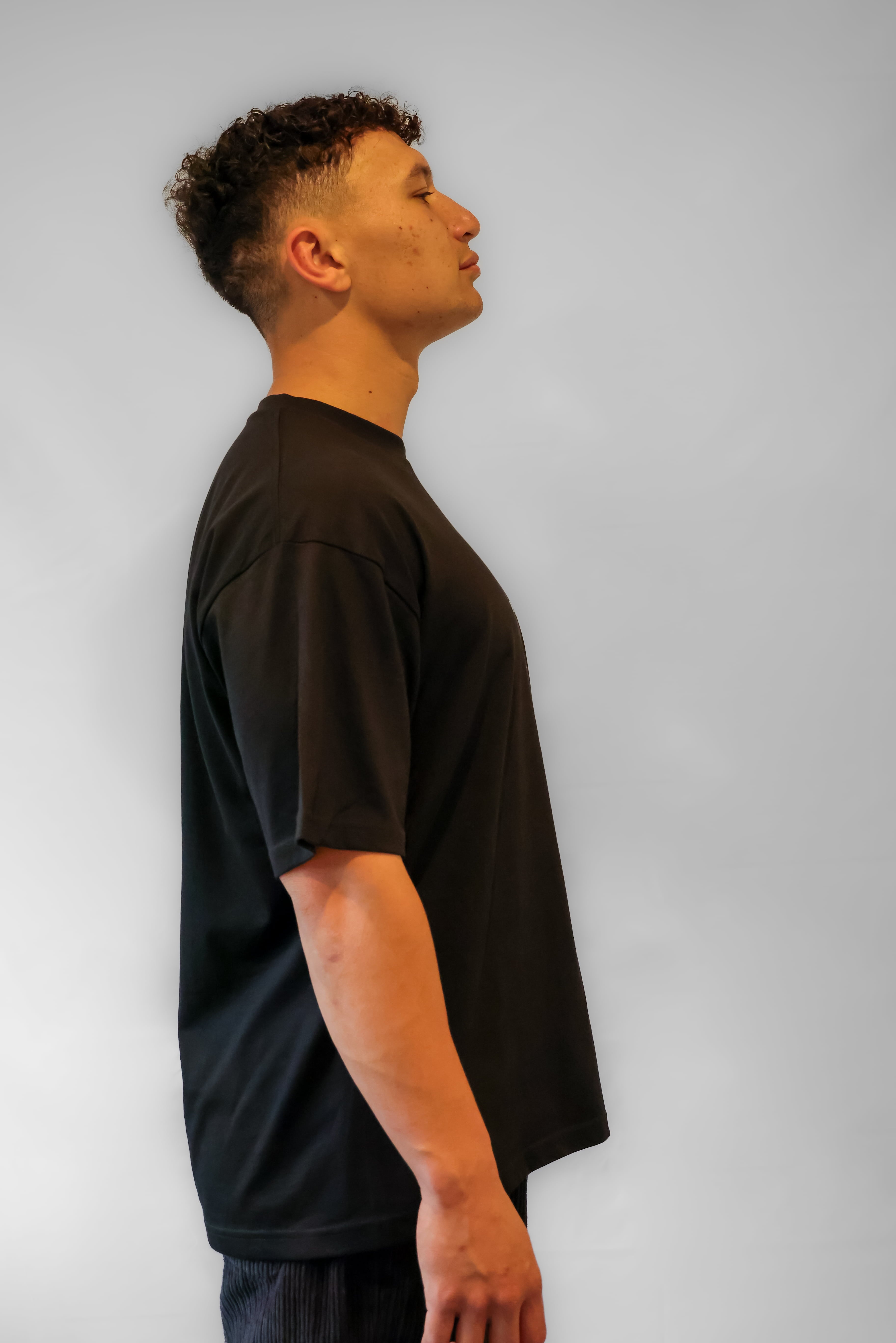 Person wearing a black t-shirt against a plain background