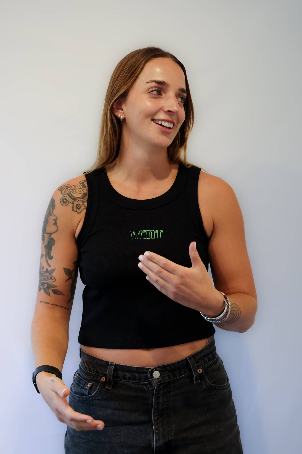 Woman wearing a black tank top with Winr logo against a grey background